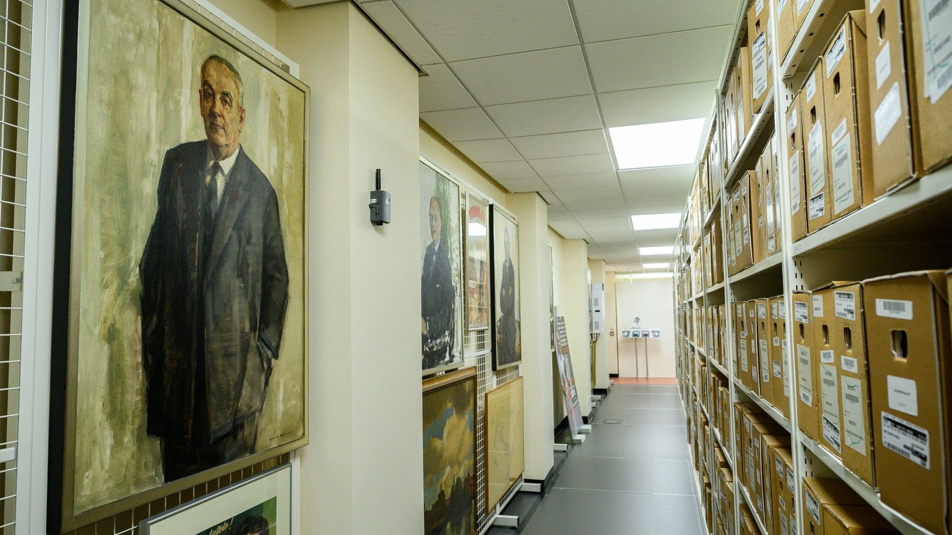 Archive corridor lined with labeled storage boxes and framed portraits