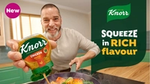 Fred Sirieix squeezes Knorr chicken stock into a pan beside the slogan “Squeeze in rich flavour.”