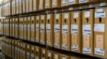 Rows of labeled cardboard inventory boxes stored on warehouse shelves