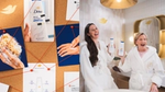 Two women in white robes laugh while holding Dove body wash bottles beside a product research board.