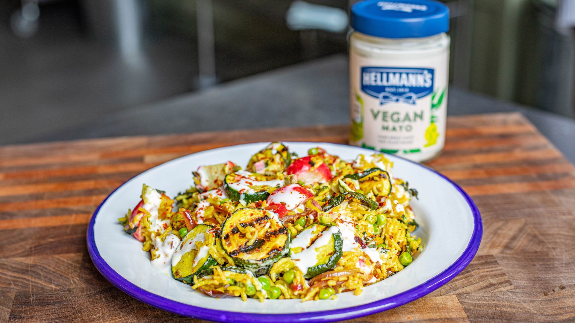 Plate of food in the foreground with a jar of Hellmann’s vegan mayonnaise in the background.