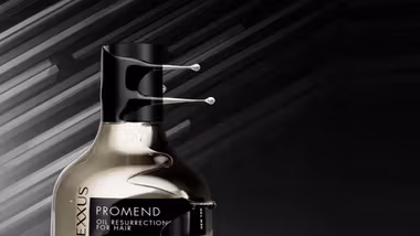 Cropped image of the top half of a gold bottle of Nexxus Promend hair treatment.