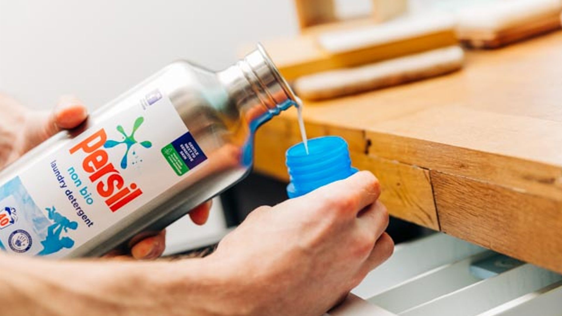 Person pouring Persil out of the new Loop stainless steel bottle