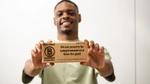 A man holding a small plank that says "Certified B Corporation".