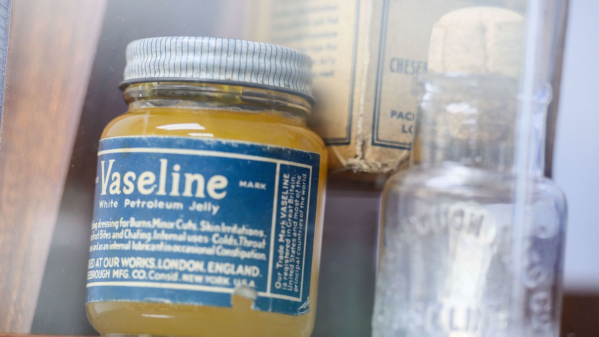 Vintage jar of Vaseline petroleum jelly displayed beside an old glass bottle.