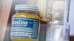 Vintage jar of Vaseline petroleum jelly displayed beside an old glass bottle.