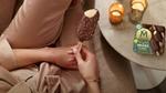 Woman sitting  beside a table with a multi-pack of vegan Mini Magnums and holding a vegan Mini Magnum in her hand