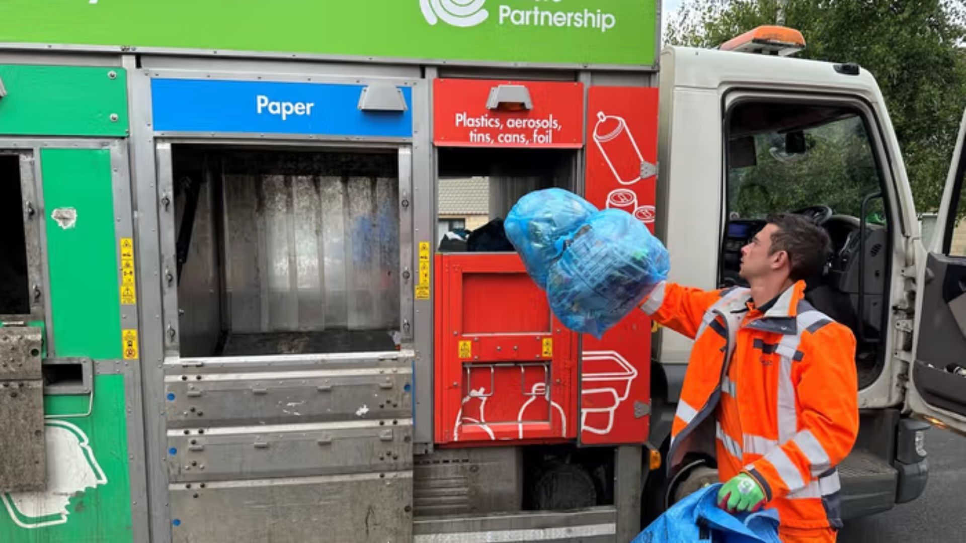 Person throwing a bag into a recycling collection truck