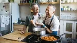 Two men laughing while cooking in a kitchen.