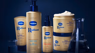 Products from Vaseline’s Radiant X collection, including Nourishing Body Lotion and Hydrating Body Oil. Packaging is golden on a dark blue background.