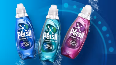 A blue, turquoise and pink bottle of Persil Wonder Wash on a teal backdrop.