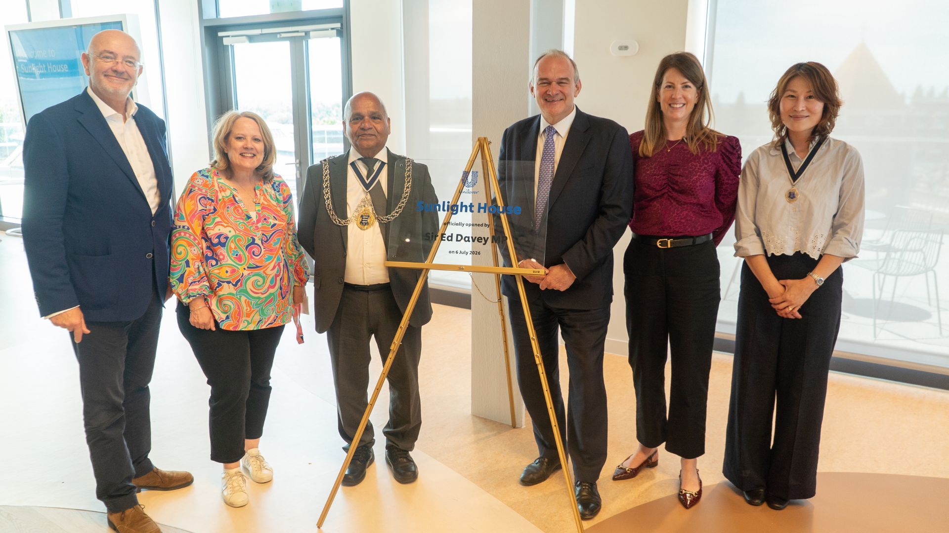 Group of attendees standing beside a commemorative plaque marking the opening of Sunlight House, Unilever's new UK and Ireland headquarters in Kingston upon Thames.