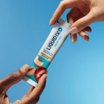 Hand holding Liquid I.V. Sugar-Free sachet on blue background.