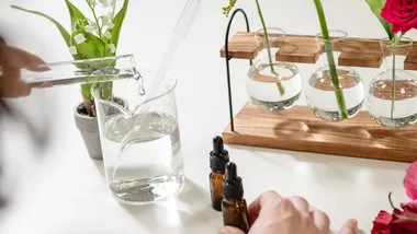 Image of four rounded test tubes in a wooden holder, containing a variety of flowers including a red rose.