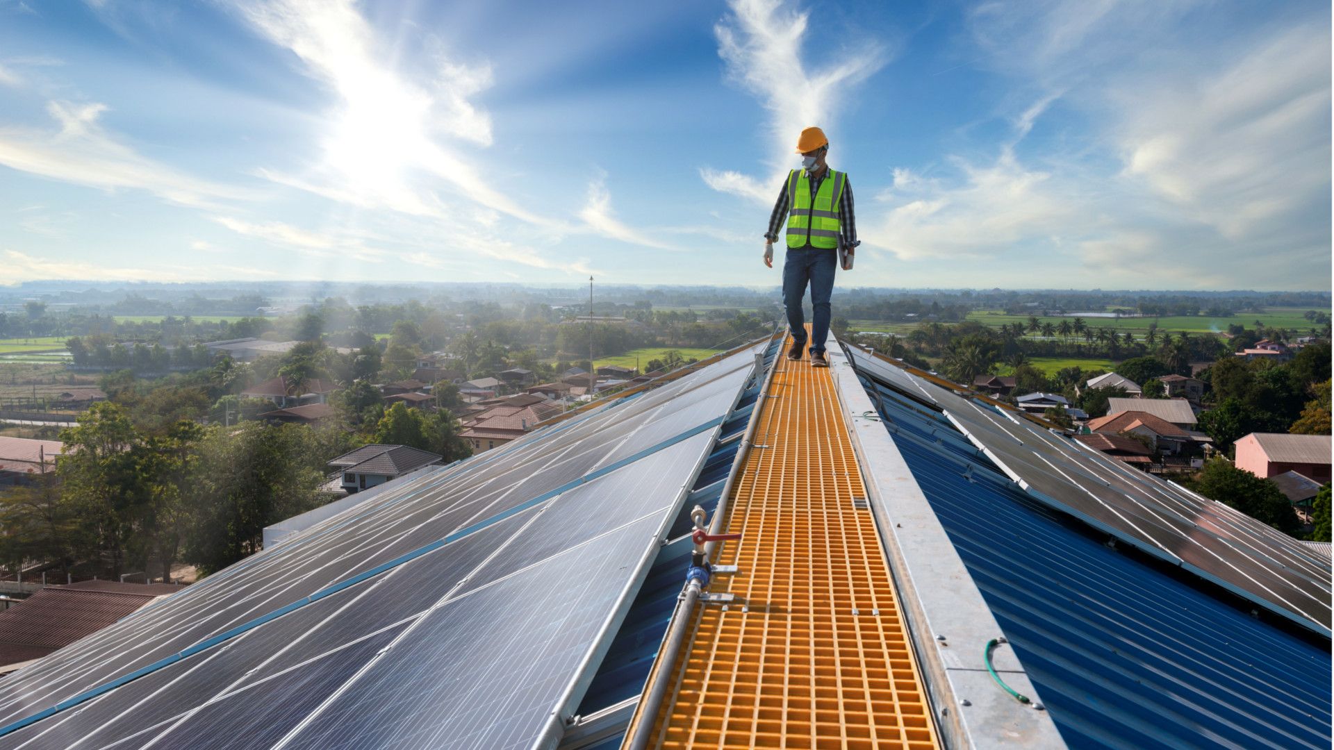 Engineer walking along the roof of a building, checking the maintenance of its energy-producing solar panels